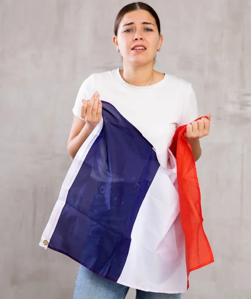 悲しいです若いです女性とともにフランスの旗で手に悲しいですポーズ悲しいで光Unicoloured背景 — ストック写真