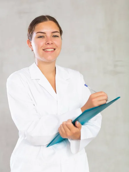 女性医師は 彼女の手に紙のフォルダを保持する文書でメモを取ります 高品質の写真 — ストック写真