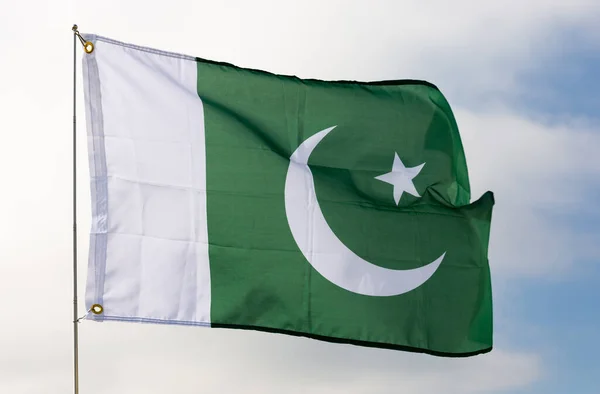 代表穆斯林多数的绿色田野的巴基斯坦国旗 白色月牙和五角星象征着进步 旗杆迎着多云的天空迎风飘扬 — 图库照片