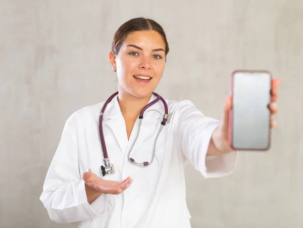 Uśmiechnięta Lekarka Białym Mundurze Polecająca Mobilną Aplikację Medyczną Wyciągająca Rękę — Zdjęcie stockowe