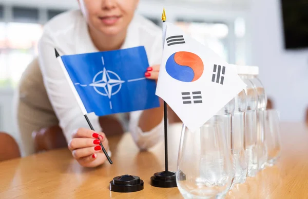 将韩国国旗和北约国旗放在女性办公室协调员手中 为涉及安全和加强伙伴关系的谈判准备会议室 有选择地确定重点 — 图库照片