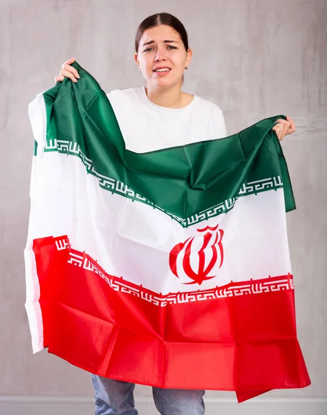 悲伤的年轻女子 双手拿着伊朗国旗 悲伤地在浅色的单色背景下摆姿势 — 图库照片
