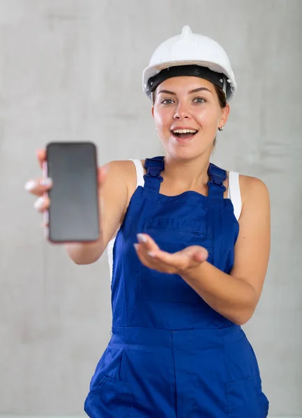 Молода Позитивна Жінка Комбінезоні Позує Студії Мобільним Телефоном — стокове фото