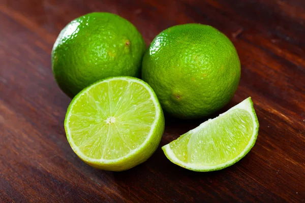 stock image Picture of cut fresh raw green limes on wooden table in home kitchen