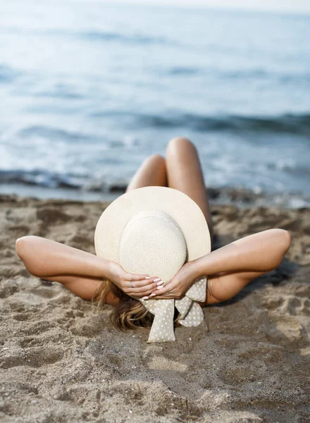 水着姿の若い女性の閉鎖と海の岸で日光浴を取る帽子 — ストック写真