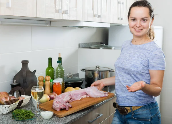 キッチンでの調理のウサギの肉と若い女性持株木材を笑顔の肖像画 — ストック写真