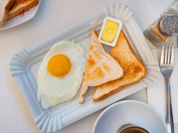 在自助餐厅的饭桌上 用烤土司和配料黄油把煎蛋倒入盘中 — 图库照片