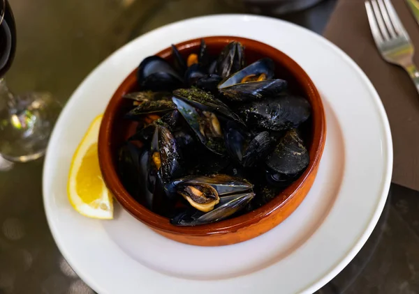 貝で蒸しムール貝を食欲をそそり ガーリックバターソースと粘土ボウルにレモンウェッジを添えて 地中海のシーフード前菜 — ストック写真