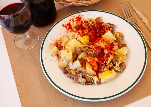 stock image Galician dish of stewed pigs ear with red pepper and potatoes at plate on table