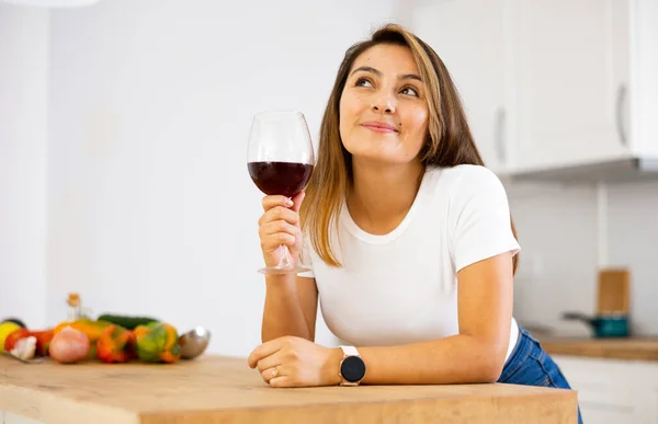 현대식 주방에서 포도주를 컵가지고 기뻐하는 여인의 주부가 샐러드를 준비하고 포도주를 — 스톡 사진