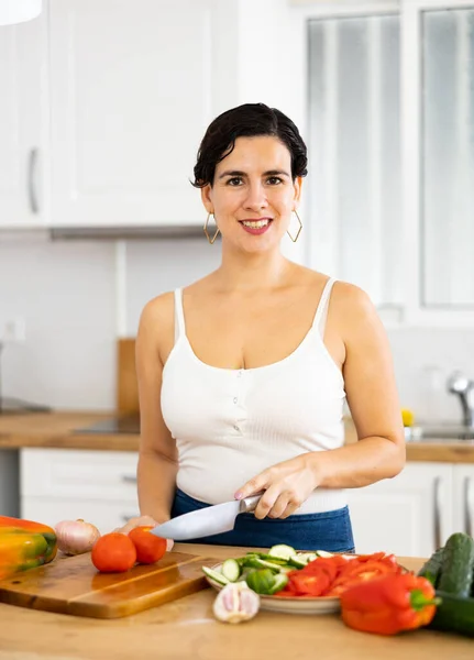 家のキッチンで夕食のための野菜サラダを準備健康的な食事の後に陽気な若いヒスパニック系の女性 — ストック写真