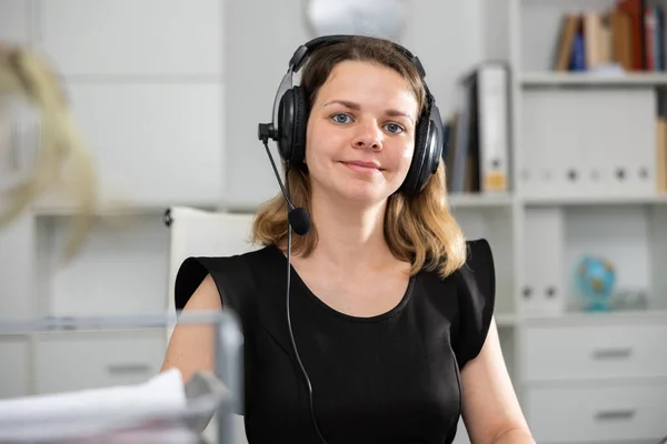 Vrouwelijke Callcenter Medewerker Met Hoofdtelefoon Aan Het Bureau Kijkend Naar — Stockfoto