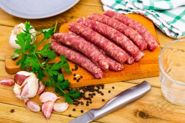 Traditional Catalan raw pork sausage longaniza ready for grilling on wooden board clipart