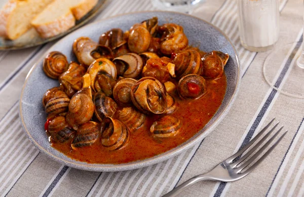 stock image Andalusian style appetizer of land snails caracoles stewed with salsa of tomatoes, garlic, rosemary, hot peppers and olive oil. Traditional Spanish cuisine