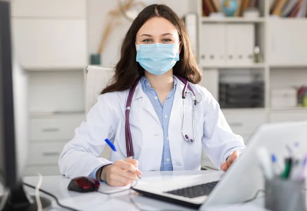 보호용 마스크를 수련의 가전염병 창궐하는 병원에서 생활을 책상에 사무실에 컴퓨터 — 스톡 사진