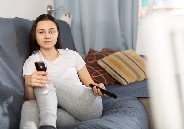 年轻而积极的女人在客厅舒服地坐在沙发上看电视 — 图库照片
