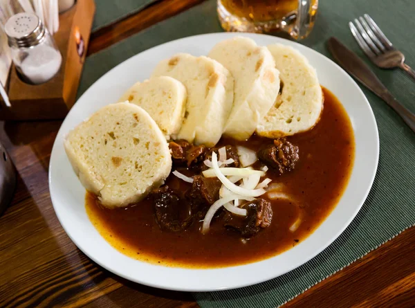 白皿の上に伝統的なチェコの餃子の飾りと煮込みビーフグーラッシュを食欲をそそる — ストック写真