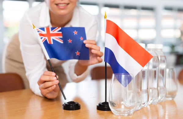 Ung Kvinna Affärskläder Sätter Flaggor Nya Zeeland Och Nederländerna Förhandlingsbordet — Stockfoto