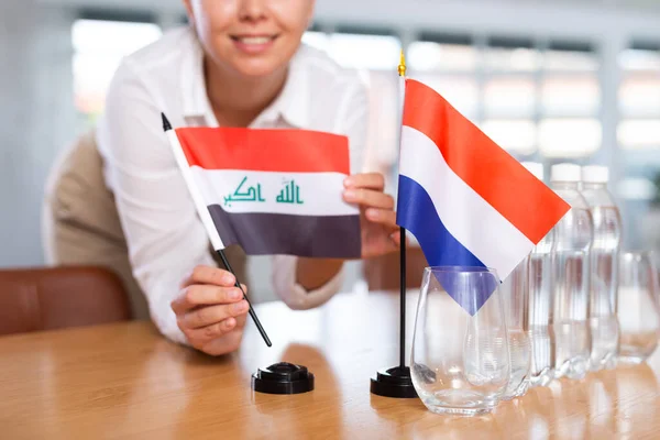 Young Woman Business Clothes Puts Flags Iraq Netherlands Negotiating Table — Stock Photo, Image