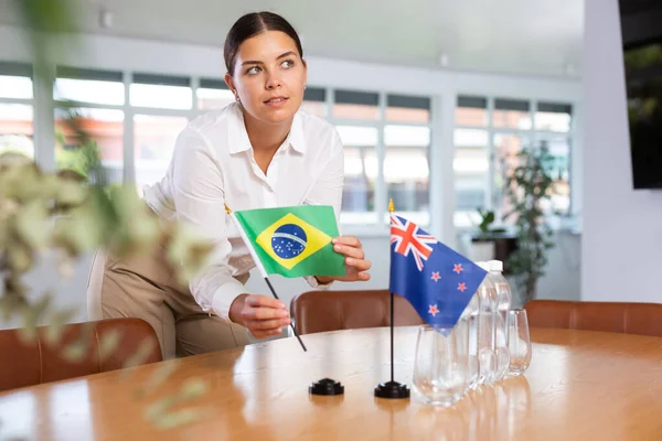 Ung Kvinna Affärskläder Sätter Flaggor Brasilien Och Nya Zeeland Förhandlingsbordet — Stockfoto