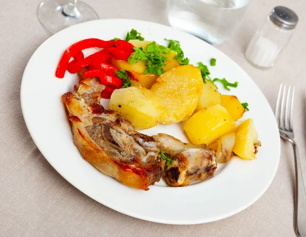 Tasty baked lamb leg slices served with fried potatoes and red pepper..