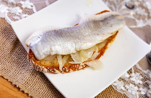 欧洲烹饪中受欢迎的小吃是一种三明治 配上少许咸鱼和洋葱 切割成环状 特写图像 — 图库照片
