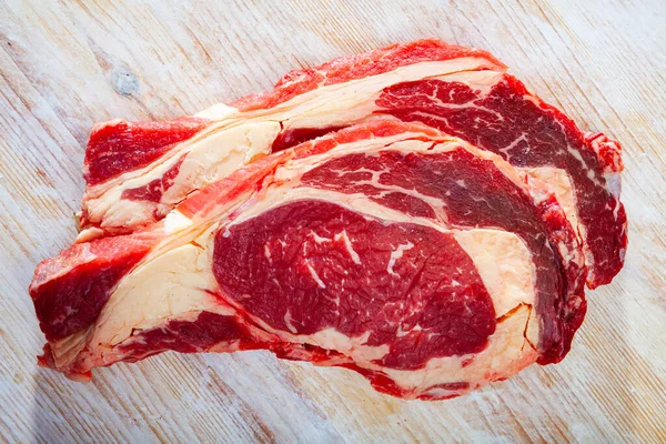 ハーブと木の背景に新鮮な生牛ステーキ — ストック写真
