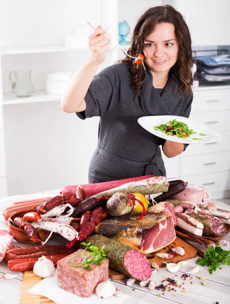 stock image Young slender woman chooses healthy food, but not sausages and smoked meat