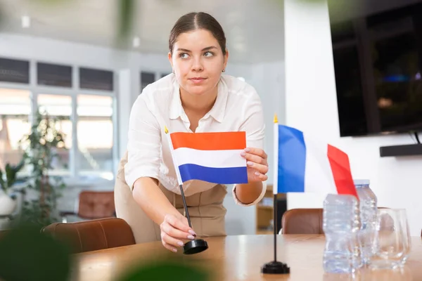 ビジネス服の若い女性は オフィスで交渉テーブルにフランスとオランダの旗を置く — ストック写真