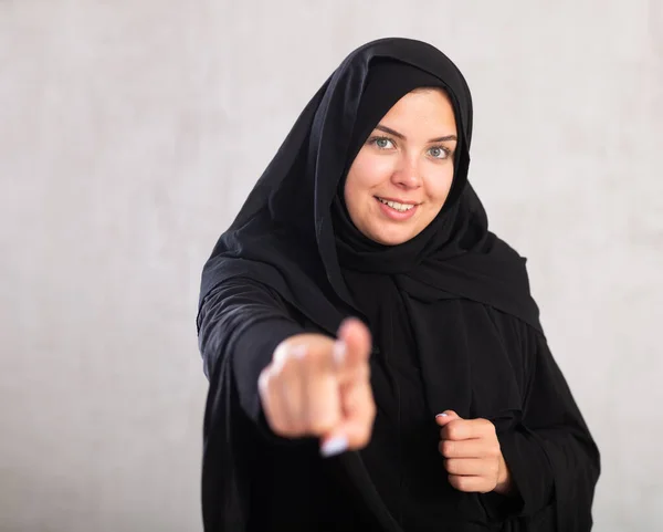 何かを指摘する伝統的なイスラムの服を着た笑顔の若い女性 — ストック写真