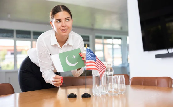 ビジネス服の若い女性は オフィスで交渉テーブルにパキスタンと米国の旗を置く — ストック写真