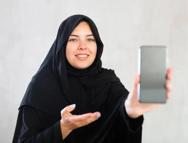 Vrolijke Jonge Moslim Dame Zwart Traditionele Hijab Tonen Nieuwe Telefoon — Stockfoto