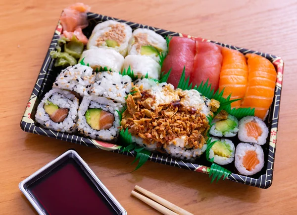 Sushi set roll of uramaki and nigiri is decorated with imitation grass, served on rectangular plate. Traditional Japanese Asian cuisine, gastronomy