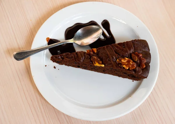 Sweet delicate triangular piece of chocolate-nut pie, poured with liquid chocolate, is served on plate. Gastro tourism, low-calorie desserts, wholesome nutrition