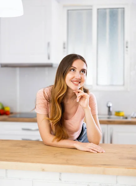 Portrait of contented joyful young woman in home kitchen