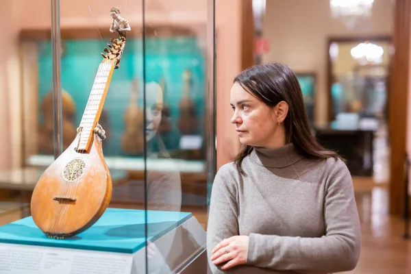 歴史博物館で中世の楽器の展覧会を訪問興味のある大人のブルネットの肖像画 — ストック写真
