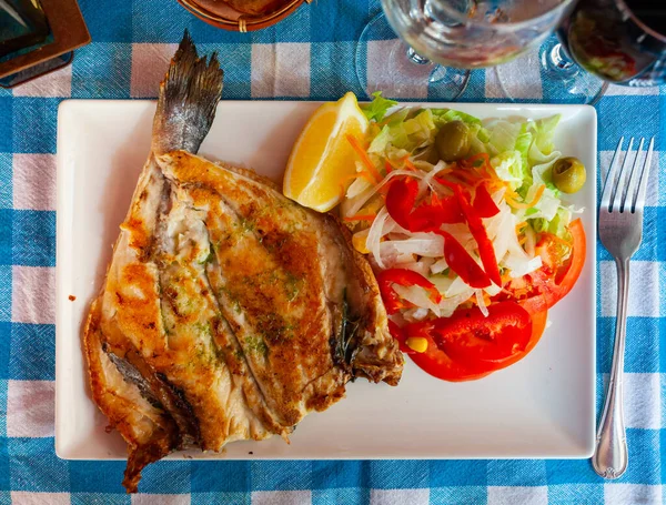 Baked bream with salad of vegetables on square plate