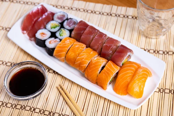 用生鱼片 金枪鱼和鳄梨卷和酱油一起食用的一套美味的黑鬼寿司 乌拉麦和诺里玛基卷 日本菜 — 图库照片