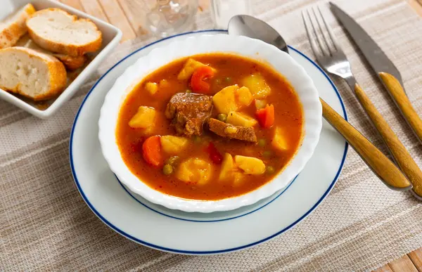 Restaurants guests will have hearty lunch - pork stewed with vegetables, potato, carrots and green peas in spicy gravy, served with slices of bran baguette