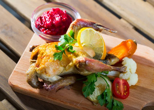 Baked in oven poultry dish with cranberry sauce and grilled vegetables on wooden board