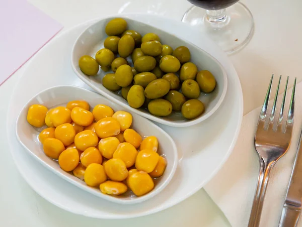 おいしい緑の未使用のオリーブと漬物ルピン豆の2つの白いプレート — ストック写真