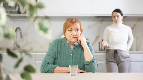 stock image Distressed mature woman after a conflict with her daughter sitting at the table in the home kitchen