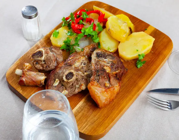 Oven baked lamb leg garnished with potatoes and peppers