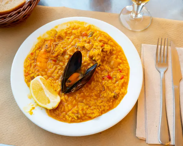 Creamy paella with chicken and seafood served with lemon quarter.