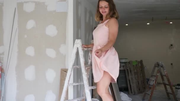 Ελκυστικό Κορίτσι Μπεζ Φόρεμα Θέτει Σκάλα Ένα Δωμάτιο Που Ανακαινίζεται — Αρχείο Βίντεο