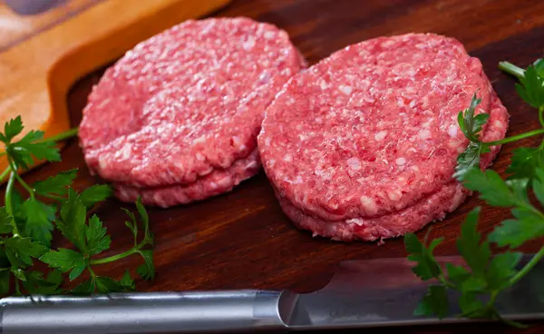 Image of raw burger cutlet and greens before cooking, nobody
