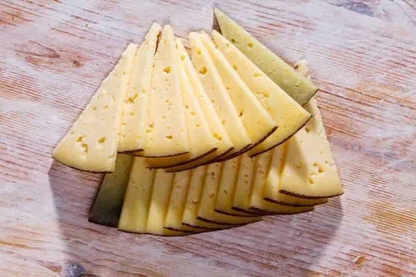 おいしいスライス半ハードチーズから牛ミルク上の木製テーブル — ストック写真