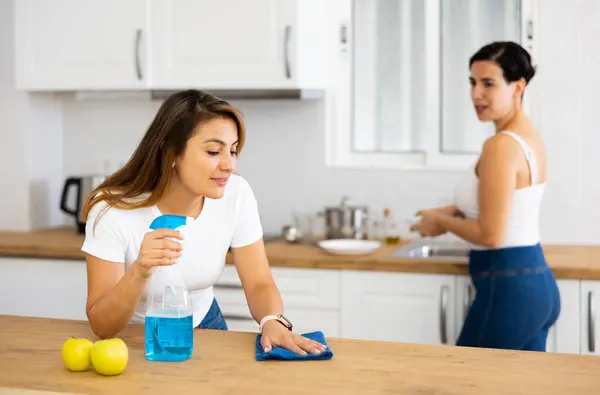 Young Woman Cleaning Countertop Kitchen While Friend Washes Dishes — Stock Photo, Image