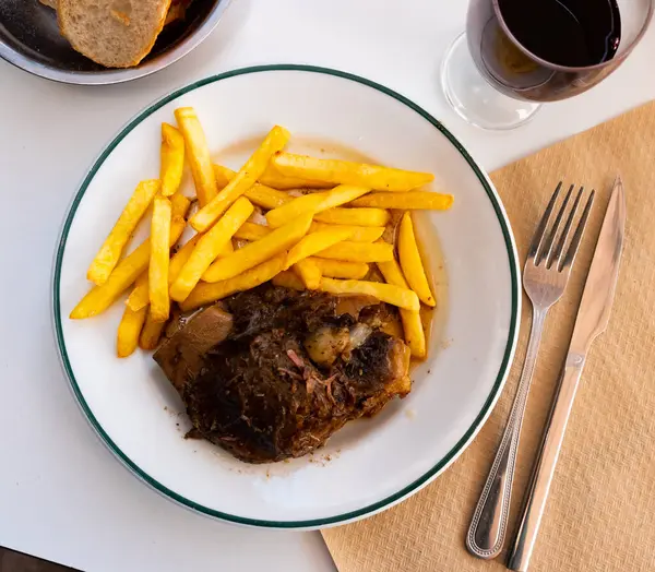 Delicious oven roasted pork cheeks served with side dish of crispy french fries for dinner..
