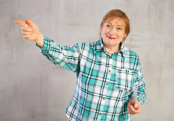 stock image Happy mature lady standing with confident smile pointing to side